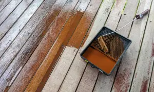 Malowanie boazerii na tarasie. Drewniane deski odzyskują blask dzięki brązowej lazurze.