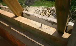 Drewniane belki konstrukcyjne, widoczna impregnacja drewna, przygotowane do budowy dachu.