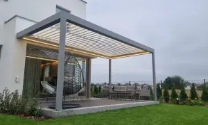 Nowoczesna pergola z oświetleniem LED. Zastanawiasz się, czym pomalować pergole? Ta szara konstrukcja świetnie komponuje się z meblami ogrodowymi i zielenią.