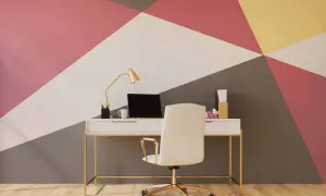 Nowoczesne wzory malowania ścian w geometryczne kształty. Biurko z laptopem i krzesłem na tle kolorowej ściany.