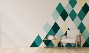 Nowoczesne wzory na ścianie z taśmy malarskiej tworzą geometryczny, kolorowy akcent. Jasna ściana i drewniana podłoga kontrastują z rombami w odcieniach zieleni i żółci.