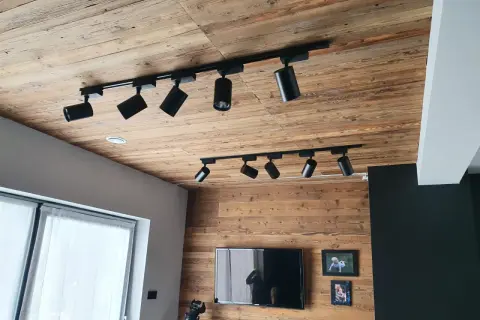 Drewniany sufit z szynoprzewodami i reflektorami to świetny pomysł na sufit w pokoju.