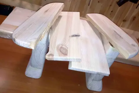Drewniany taboret DIY, w trakcie budowy, z widocznymi słojami drewna i zaokrąglonymi elementami.
