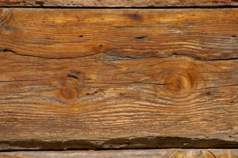 Słoje drewna tworzą piękny, naturalny wzór. Widoczne są sęki i pęknięcia, nadające mu charakterystyczny efekt starego drewna.