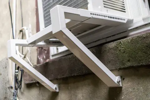 Solidne oparcie dla ramy okiennej, wykonane z białego metalu, zapewnia stabilne mocowanie klimatyzatora.