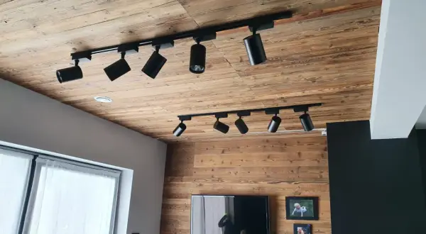 Drewniany sufit z szynoprzewodami i reflektorami to świetny pomysł na sufit w pokoju.