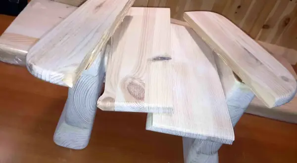 Drewniany taboret DIY, w trakcie budowy, z widocznymi słojami drewna i zaokrąglonymi elementami.