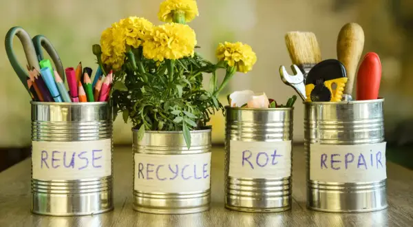 Puszki metalowe pokazują, co zrobić z odpadami: REUSE (nożyczki, kredki), RECYCLE (kwiaty), ROT (skorupki jajek), REPAIR (narzędzia).