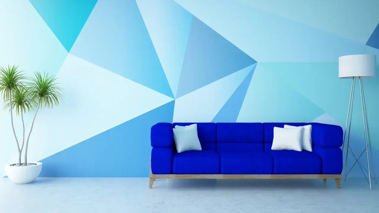 Niebieska sofa i roślina na tle ściany z geometrycznym, nietypowym malowaniem ścian w odcieniach błękitu.