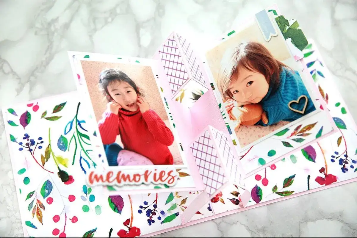 Odkryj, scrapbooking co to! Ręcznie robiona kartka z dwoma zdjęciami uroczych dziewczynek, ozdobiona akwarelowymi liśćmi i napisem 